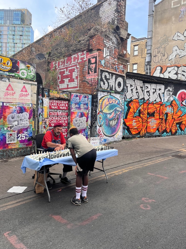 Two men playing chess in Shoreditch, London — graffiti walls and ruined brickwork behind them
